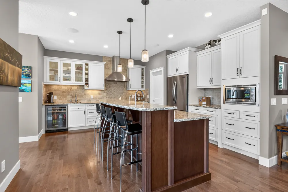Chef's kitchen with maple cabinetry, granite counters and a stone tile backsplash.